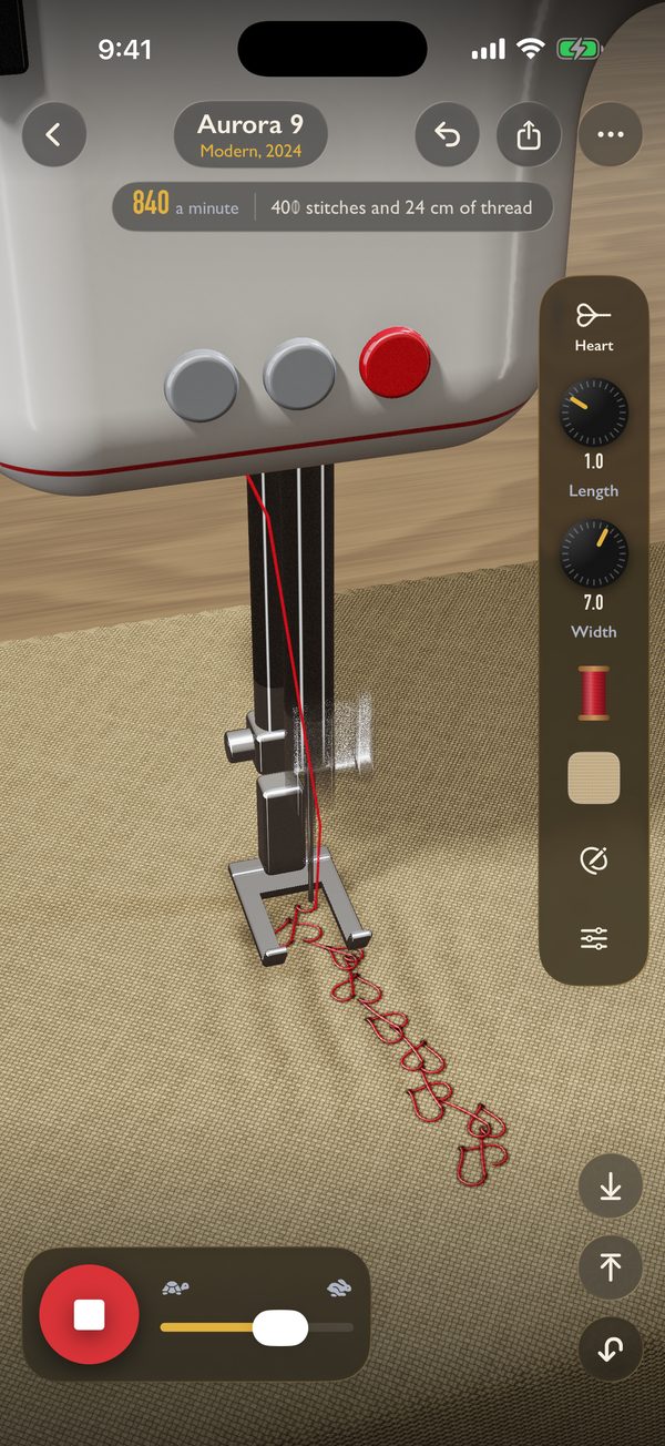 A computerized machine sewing a row of red hearts on linen.